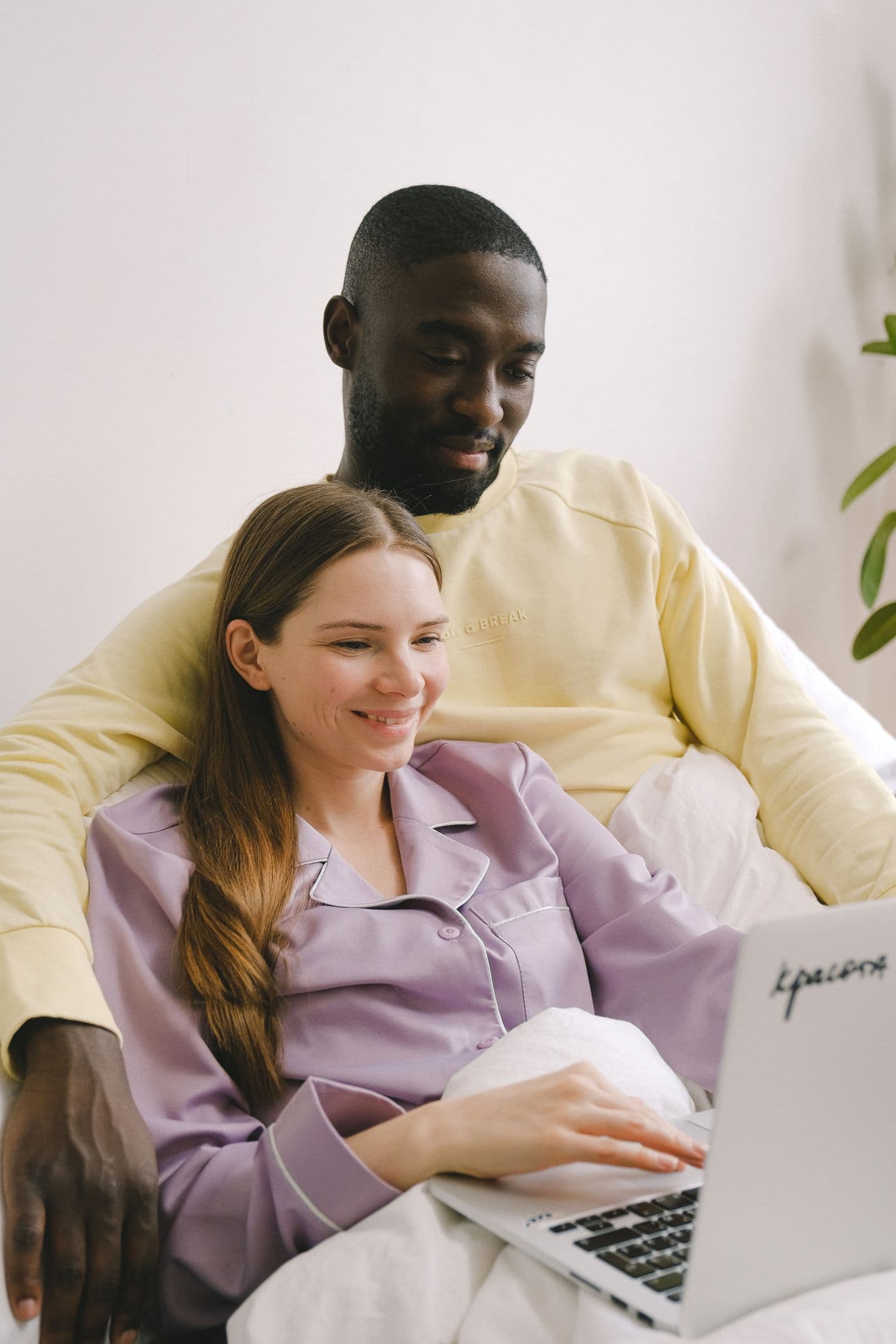 A couple relaxing at home together, smiling at a laptop